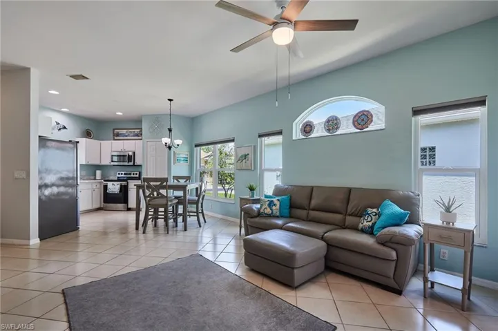 Living room with light tile patterned floors, a ceiling fan, a chandelier, and recessed lighting
