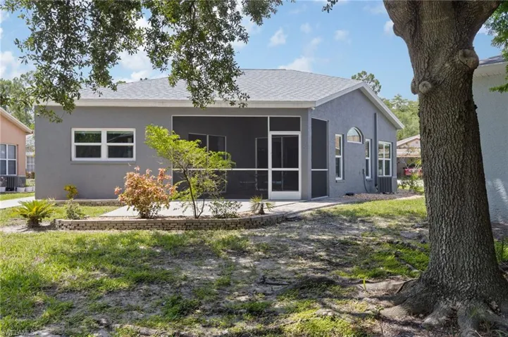 Rear view of property with stucco siding, a sunroom, and roof with shingles