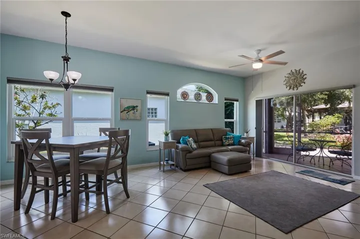 Living area with a chandelier, plenty of natural light, a ceiling fan, and light tile patterned flooring