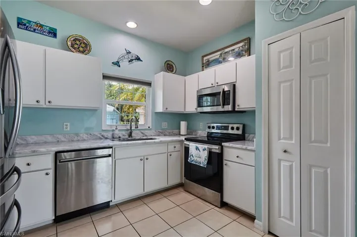 Kitchen with stainless steel appliances, light countertops, white cabinets, light tile patterned floors, and recessed lighting
