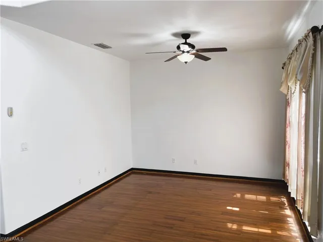Empty room with dark hardwood / wood-style floors and ceiling fan
