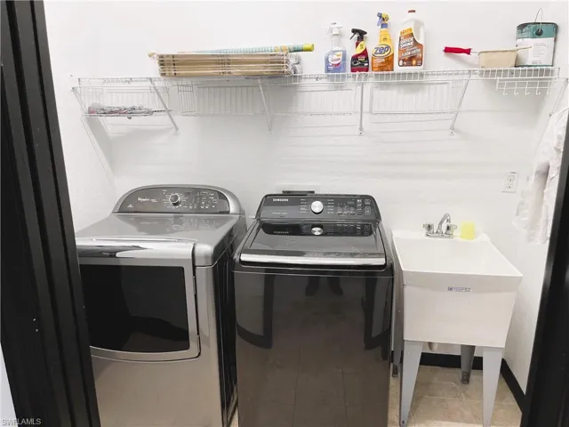 Laundry room with sink, tile patterned flooring, and washing machine and dryer