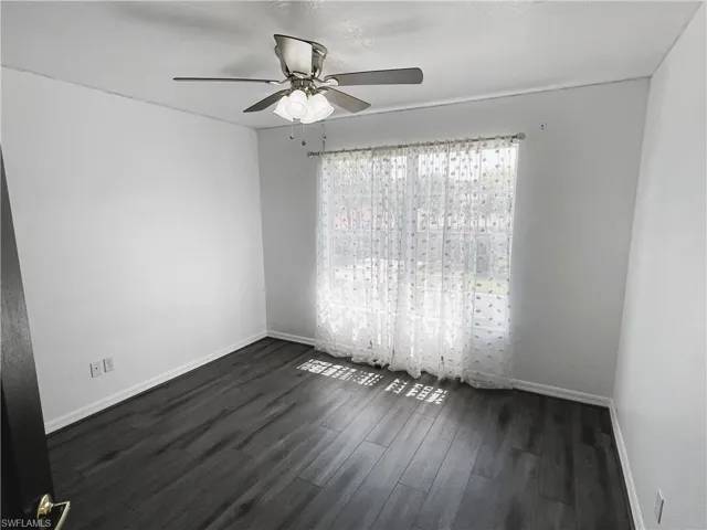 Unfurnished room with dark hardwood / wood-style flooring and ceiling fan