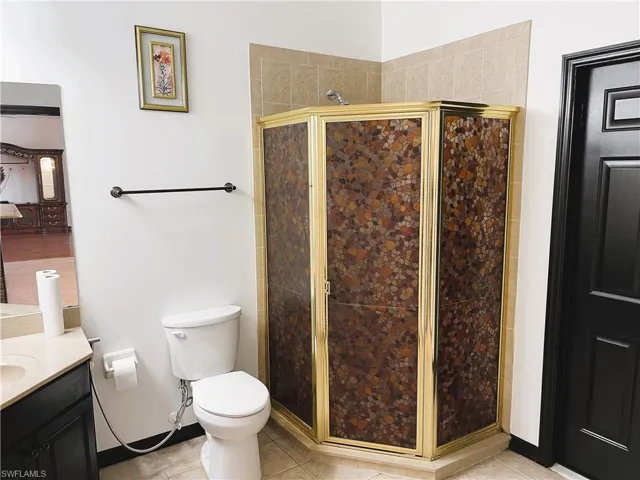 Bathroom featuring tile patterned flooring, vanity, toilet, and a shower with shower door