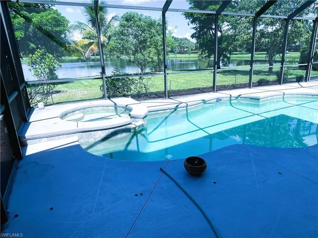 View of swimming pool featuring a lanai, a yard, an in ground hot tub, and a water view