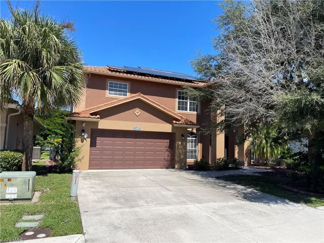 Mediterranean / spanish-style home featuring a garage, solar panels, central AC unit, and a front yard