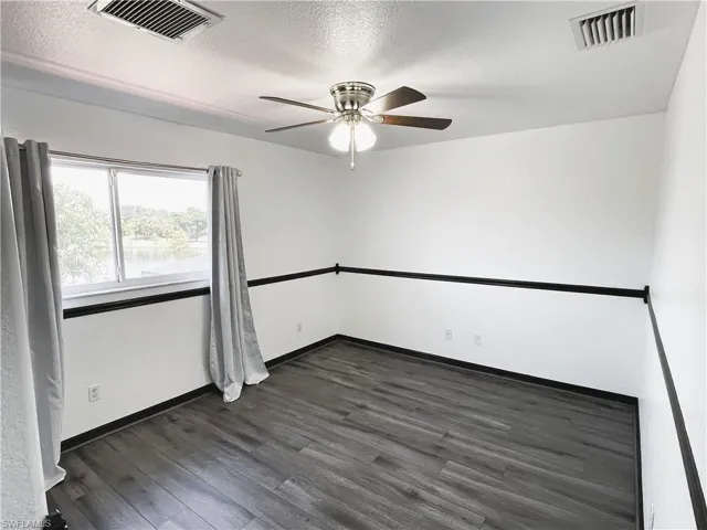 Empty room featuring a textured ceiling, dark hardwood / wood-style floors, and ceiling fan