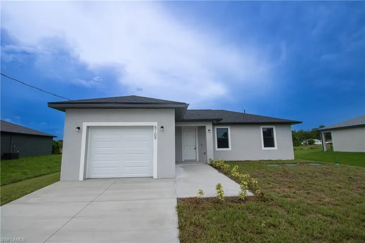 Ranch-style home with a garage, stucco siding, driveway, and a front yard.