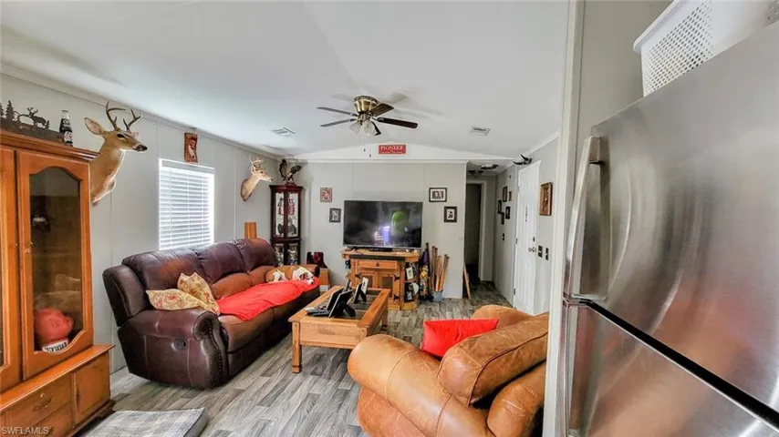 Living room with ceiling fan, wood-type flooring, and vaulted ceiling