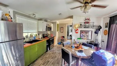 Kitchen featuring appliances with stainless steel finishes, light hardwood / wood-style floors, sink, green cabinetry, and white cabinets