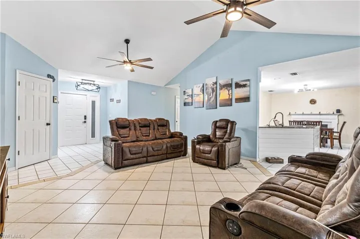 Living room with light tile patterned flooring, vaulted ceiling, and ceiling fan