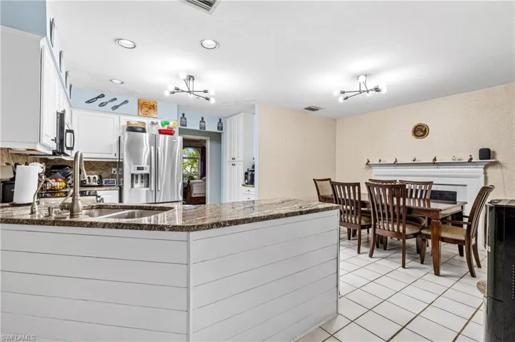 Kitchen with a peninsula, white cabinetry, dark stone counters, stainless steel appliances, and a chandelier