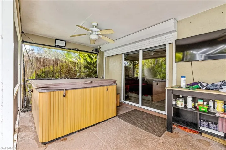 Sunroom featuring a hot tub, ceiling fan, and a patio area
