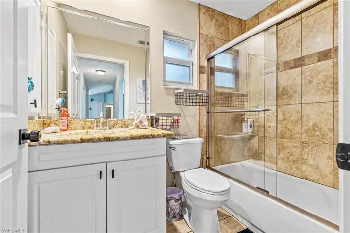 Full bathroom featuring shower / bath combination with glass door, vanity, and light tile patterned flooring