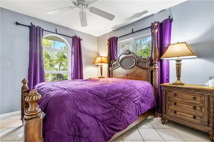 Tiled bedroom with a ceiling fan and baseboards