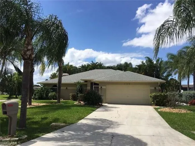 Single story home featuring a front yard, driveway, and a garage