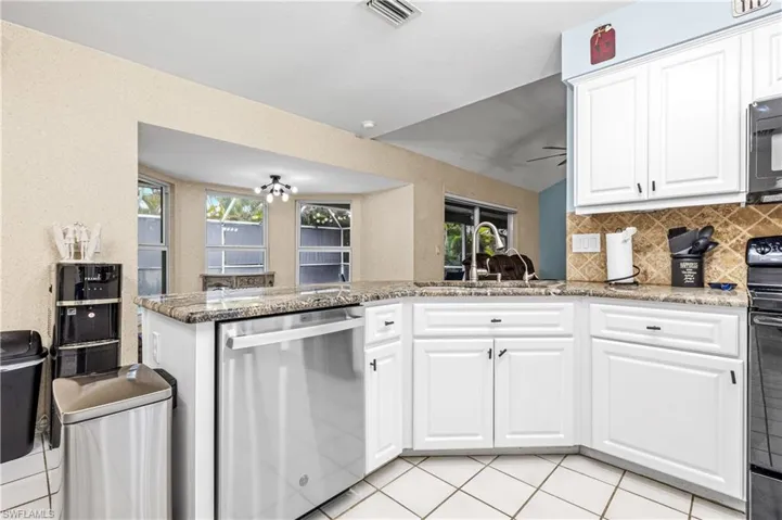 Kitchen featuring white cabinets, appliances with stainless steel finishes, light stone countertops, tasteful backsplash, and lofted ceiling