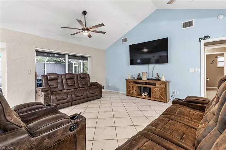Living room with a ceiling fan, high vaulted ceiling, and light tile patterned floors