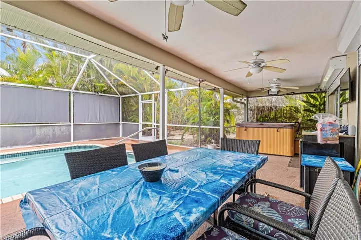 View of patio / terrace featuring a hot tub, glass enclosure, a ceiling fan, and outdoor dining area