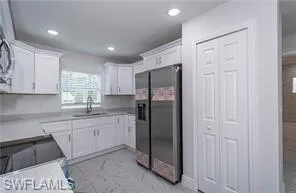 Kitchen with white cabinetry, light countertops, stainless steel fridge, recessed lighting, and electric stove