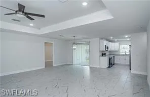 Unfurnished living room featuring a tray ceiling, recessed lighting, a ceiling fan, and light marble finish flooring
