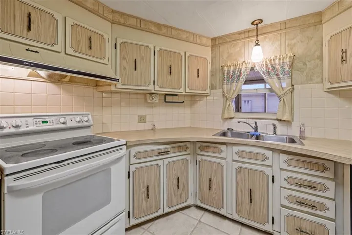 Kitchen featuring sink, tasteful backsplash, white range with electric stovetop, pendant lighting, and light tile patterned flooring