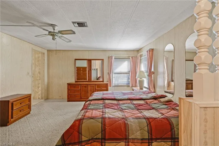 Carpeted bedroom featuring ceiling fan and a textured ceiling