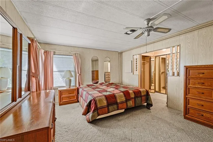 Carpeted bedroom featuring ceiling fan and wooden walls