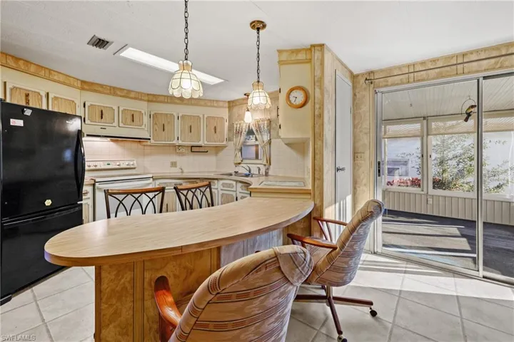 Kitchen featuring white range with electric stovetop, black refrigerator, light tile patterned floors, and tasteful backsplash