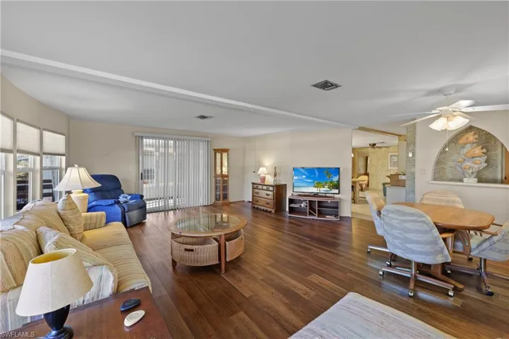Living room with ceiling fan and dark wood-type flooring