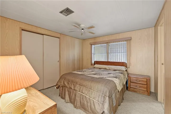 Carpeted bedroom featuring ceiling fan, a closet, and wood walls