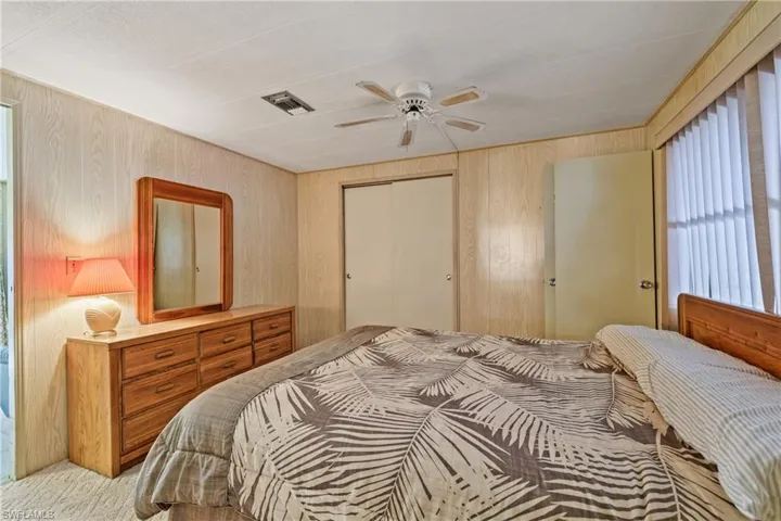 Bedroom featuring ceiling fan, a closet, light carpet, and wooden walls