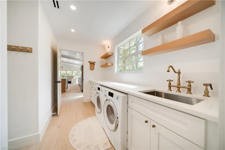 Clothes washing area with a wealth of natural light, visible vents, a sink, washer and dryer, and laundry area