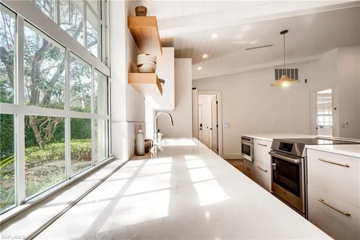 Kitchen featuring hanging light fixtures, stainless steel appliances, white cabinetry, and light countertops