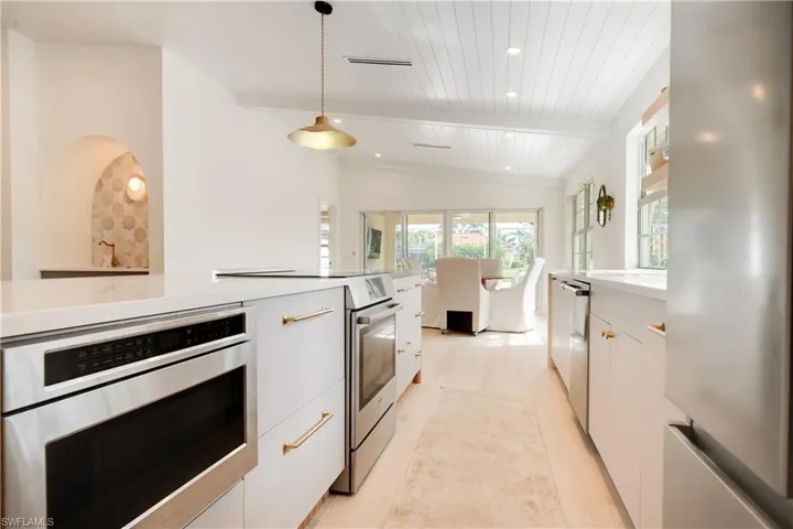 Kitchen with modern cabinets, appliances with stainless steel finishes, decorative light fixtures, light countertops, and white cabinetry