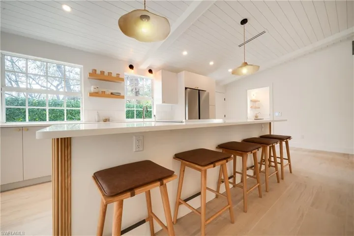 Kitchen with decorative light fixtures, freestanding refrigerator, light countertops, white cabinetry, and open shelves