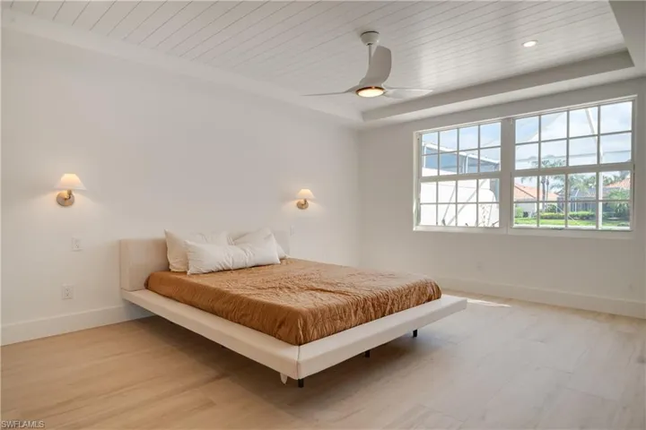 Bedroom featuring light wood finished floors, a tray ceiling, wooden ceiling, and baseboards