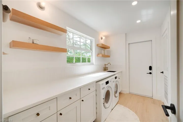 Laundry area featuring light wood finished floors, separate washer and dryer, a sink, and recessed lighting