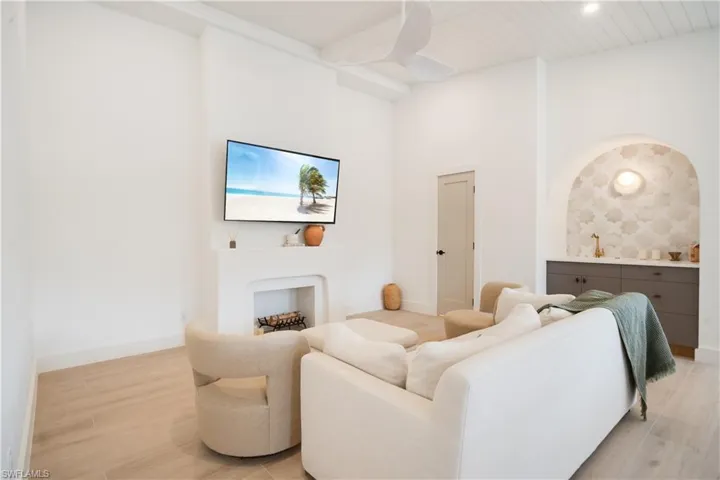 Living area with beam ceiling, baseboards, and light wood finished floors