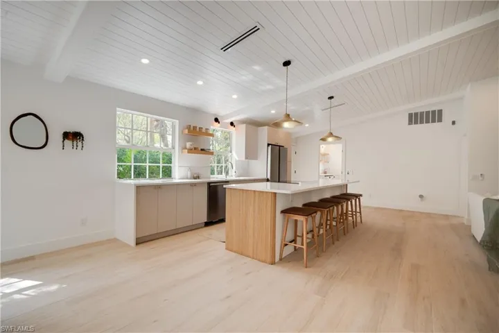 Kitchen with a spacious island, light countertops, visible vents, hanging light fixtures, and appliances with stainless steel finishes