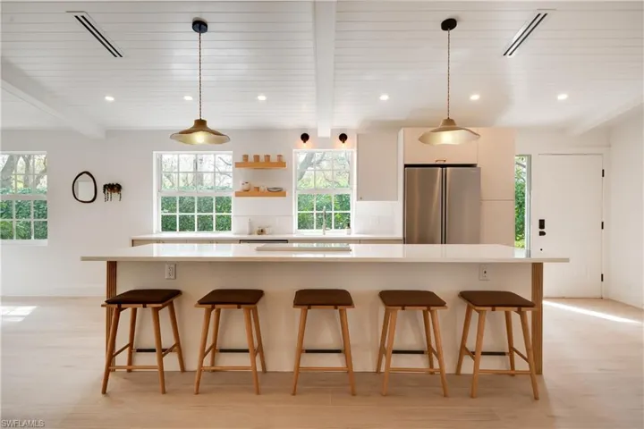 Kitchen featuring a kitchen bar, a kitchen island, light countertops, and freestanding refrigerator