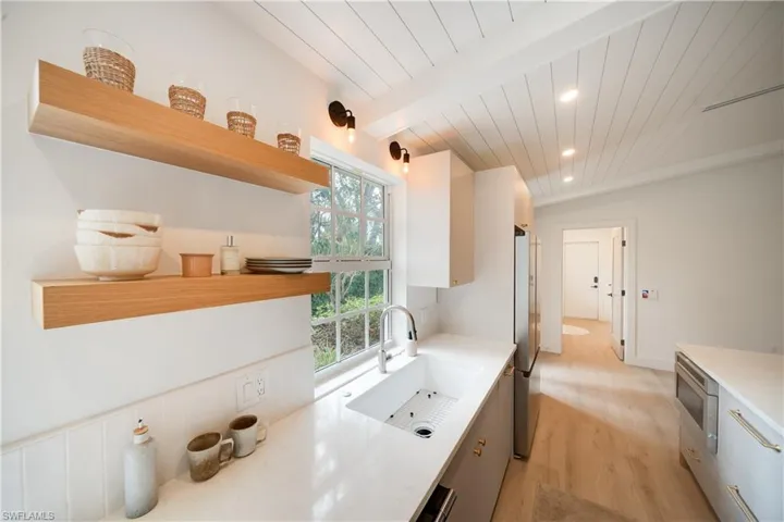 Kitchen with light countertops, a sink, and open shelves