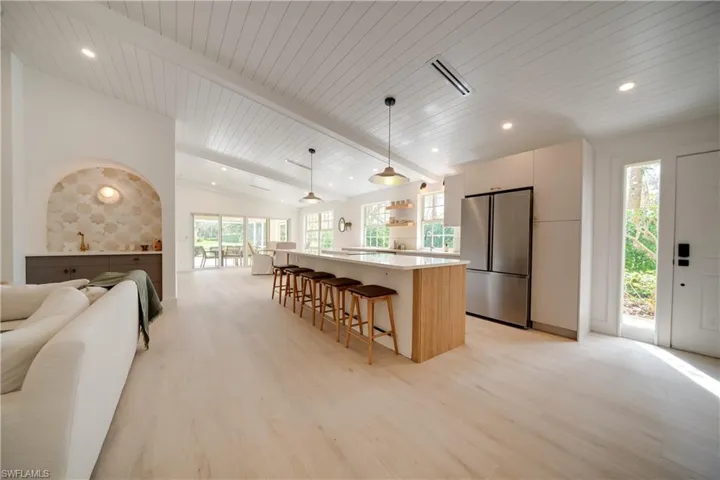 Kitchen with lofted ceiling with beams, open floor plan, freestanding refrigerator, a center island, and pendant lighting