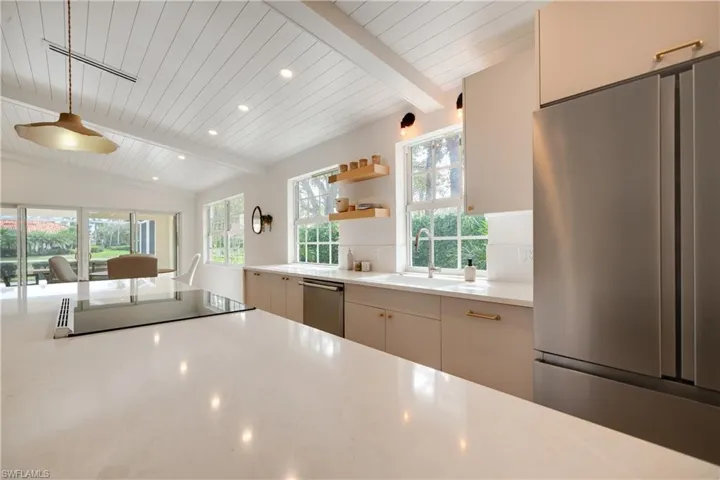 Kitchen featuring vaulted ceiling with beams, recessed lighting, stainless steel appliances, light countertops, and open shelves