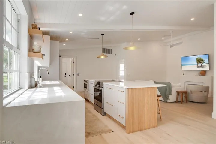 Kitchen featuring electric range, white cabinets, light countertops, open shelves, and pendant lighting