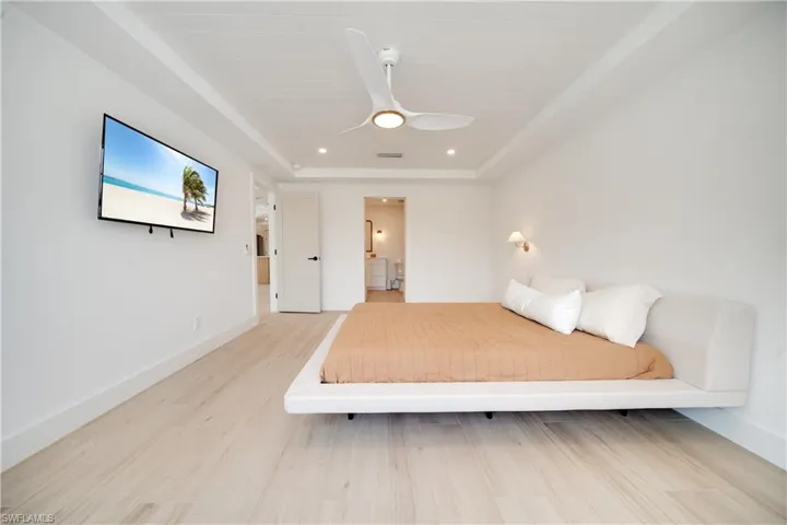 Unfurnished bedroom featuring a raised ceiling, wood finished floors, visible vents, and baseboards