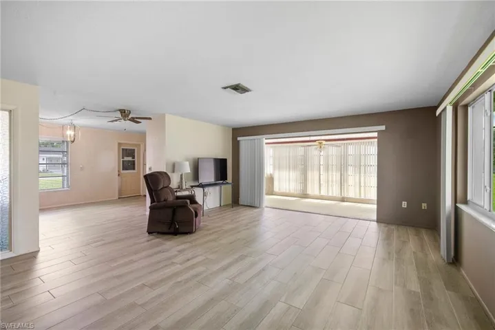 Living area featuring ceiling fan with notable chandelier and light hardwood / wood-style flooring