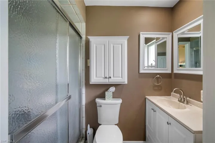 Bathroom with a shower with shower door, toilet, and vanity