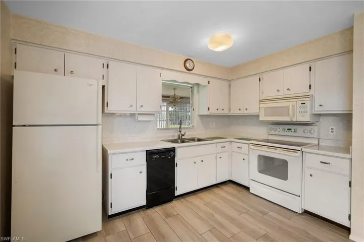 Kitchen featuring sink, decorative backsplash, light hardwood / wood-style flooring, and white appliances
