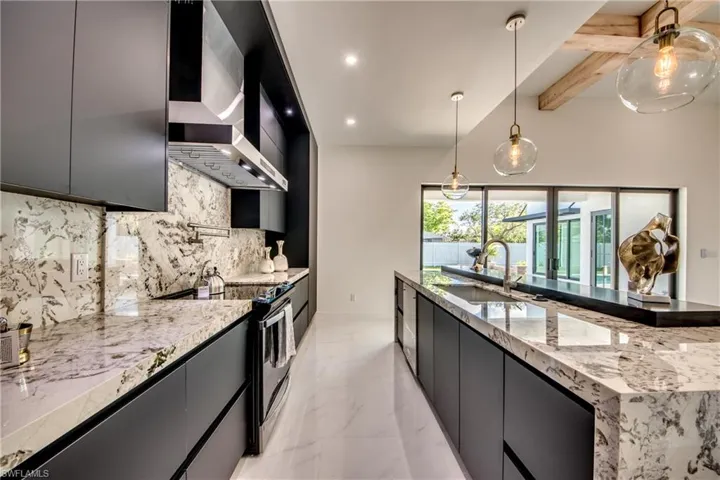 Kitchen featuring pendant lighting, backsplash, stainless steel electric stove, wall chimney exhaust hood, and beamed ceiling